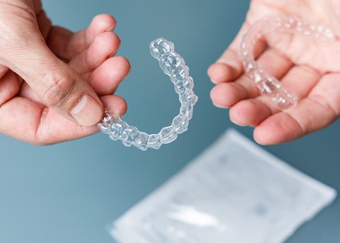 A pair of hands holding invisalign with a blurred paper at the background.