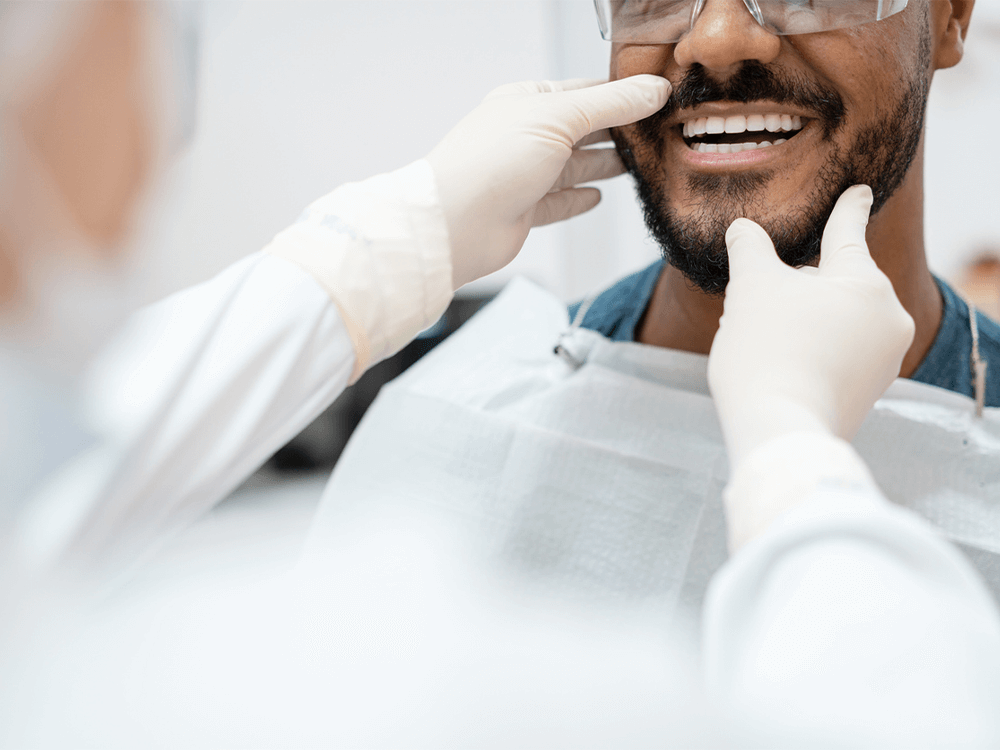 A dental professional examine the teeth of the patient with a hands with gloves.